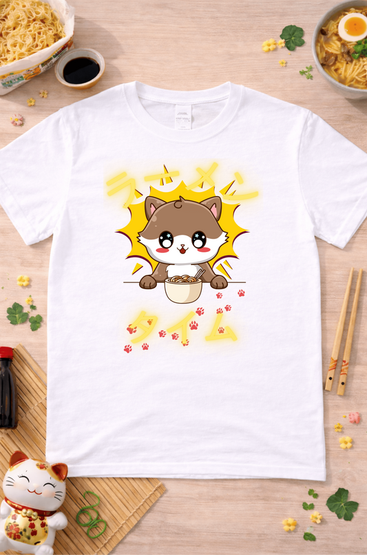 White graphic t-shirt featuring kawaii cat eating ramen with paw prints and Japanese text, styled in a warm flatlay with ramen and cozy accessories