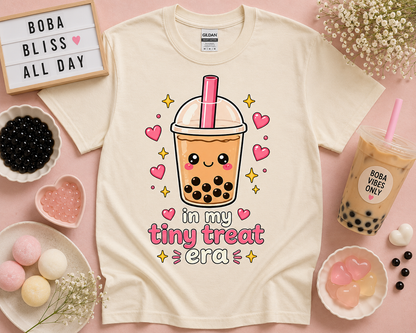 Natural cream kawaii bubble tea t shirt with in my tiny treat era design styled with cozy café inspired flat lay props for soft aesthetic fashion and cute foodie apparel lovers by New Chapter Tees