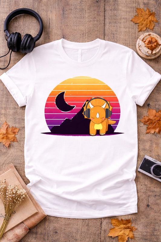 White graphic t-shirt featuring retro triceratops with headphones and vintage sunset design styled in cozy flat lay with headphones, camera, and autumn decor