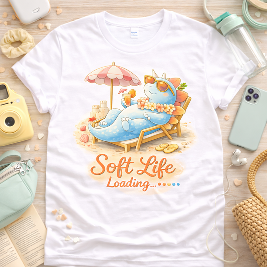Cute stegosaurus soft life loading graphic tee on white shirt with beach theme, pastel dinosaur lounging design