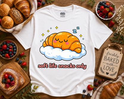White Gildan 5000 cute bakery graphic t shirt featuring sleeping croissant cloud design with soft life snacks only saying styled with bakery inspired props berries and pastries for cozy aesthetic fashion shoppers in California