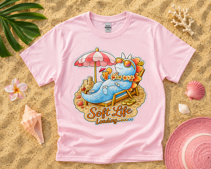 Soft Life Stegosaurus dinosaur graphic tee on light pink Gildan shirt featuring tropical beach flatlay for soft life summer fashion
