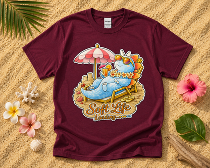 Soft Life Stegosaurus dinosaur graphic tee on maroon Gildan shirt with tropical beach flatlay cute dinosaur vacation graphic apparel